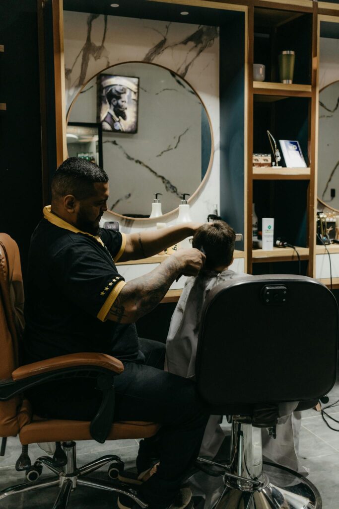 A barber skillfully cuts a child's hair in a modern salon setting, offering comfort and professional service.