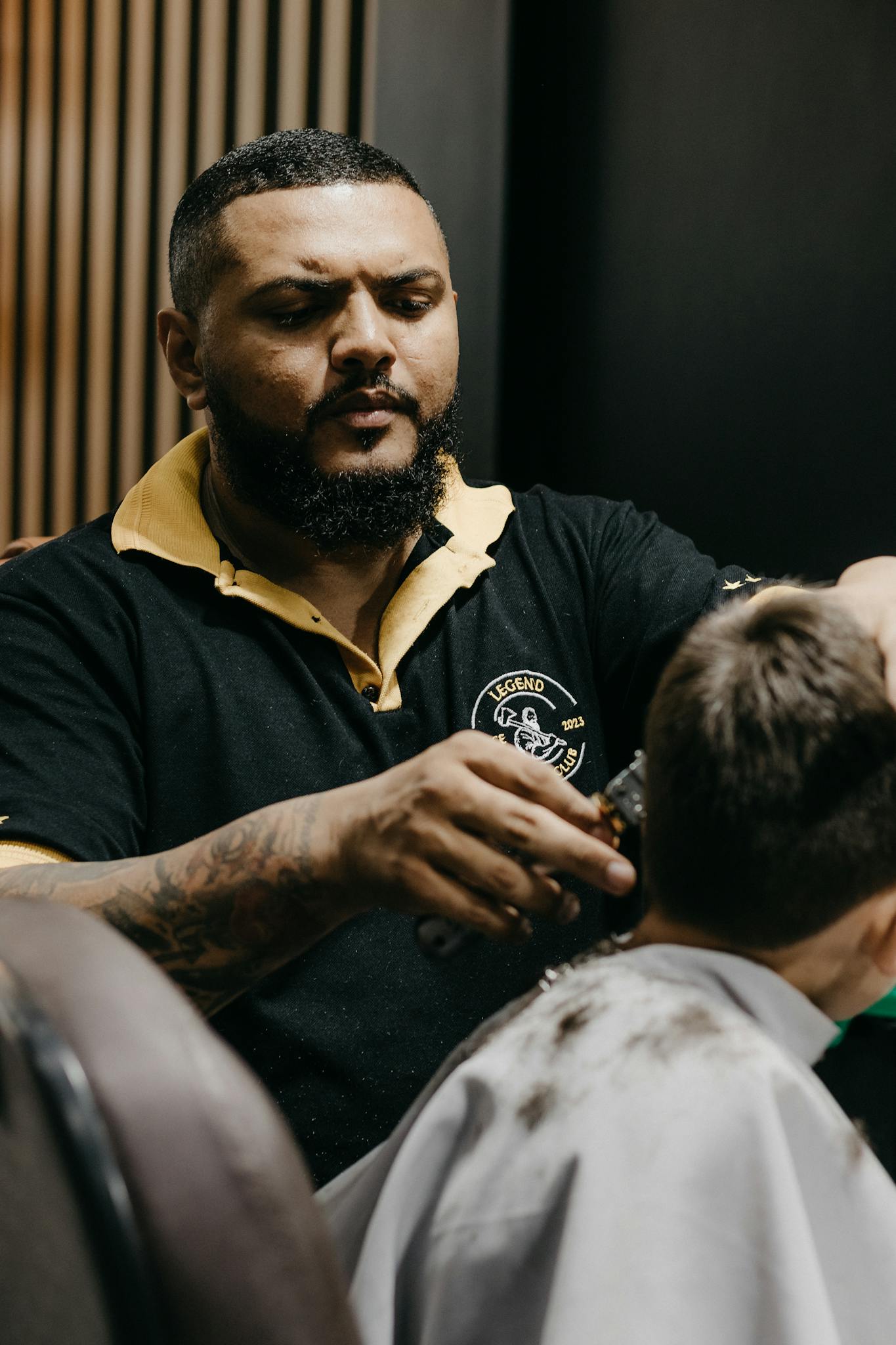Barber skillfully giving a haircut to a young boy in a modern barbershop setting.